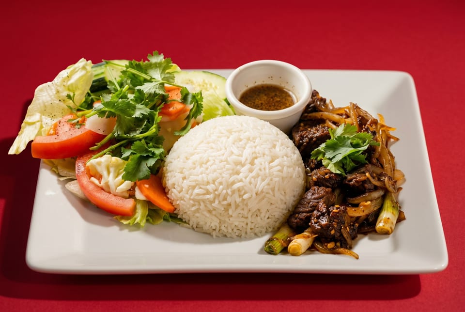 A white plate with a mound of white rice, beef stir-fry, fresh salad, and a side of sauce.